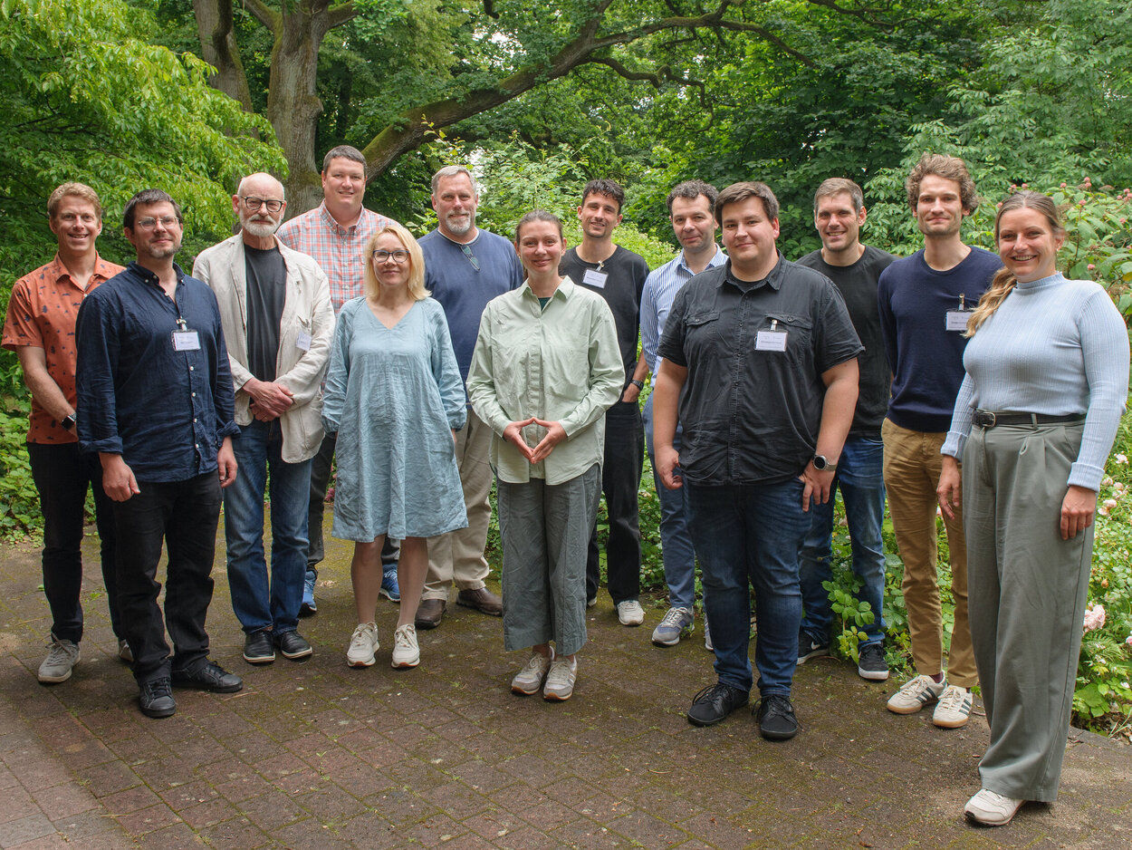 A group of people are standing in front of some trees.