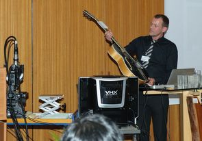 Herr Haag zeigt eine Gitarre deren Holz im Holzherkunftszentrum untersucht wurde