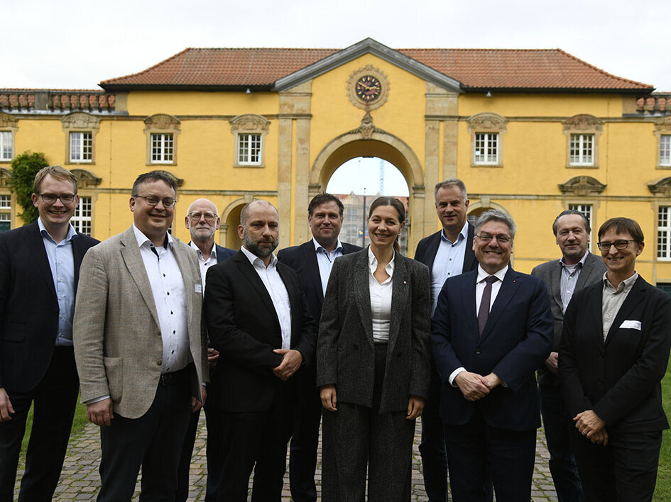 Zehn Personen stehen vor einem gelben Gebäude.