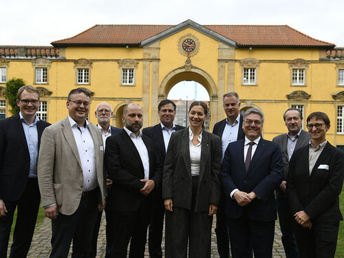 Zehn Personen stehen vor einem gelben Gebäude.