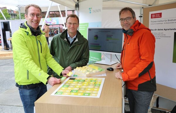 Drei Personen an einem Stand mit dem Biodiversitätsspiel des Thünen-Instituts