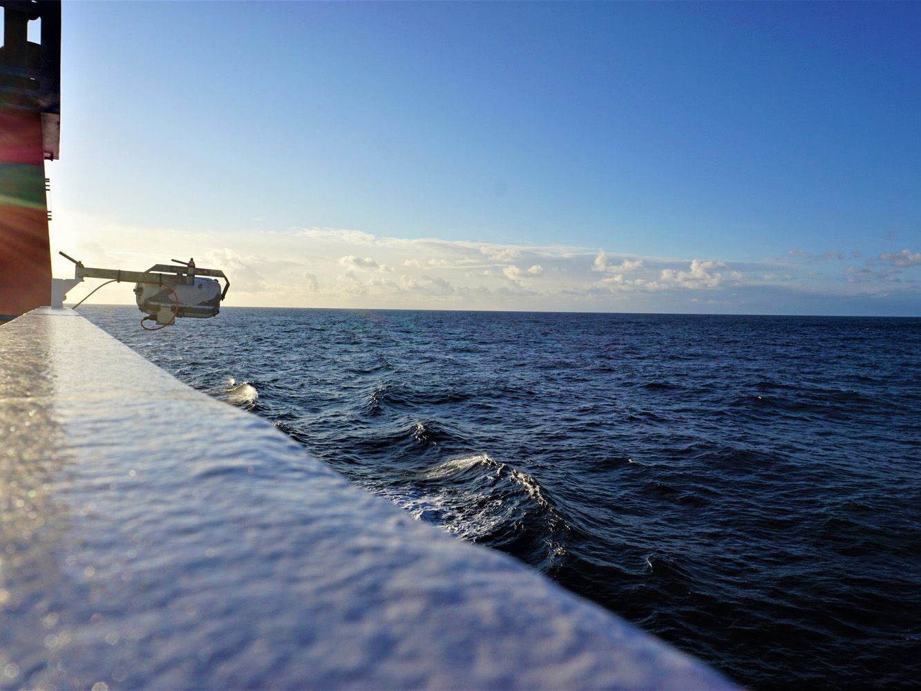 Blick über die Reling der Walter Herwig 3 auf das offene Meer mit leichtem Sonnenschein.