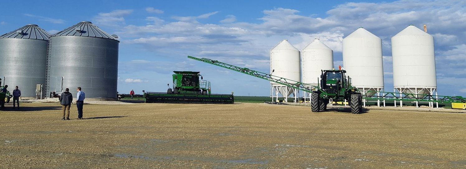 Verschiedene Landwirtschaftsmaschinen vor mehreren Getreidespeichern