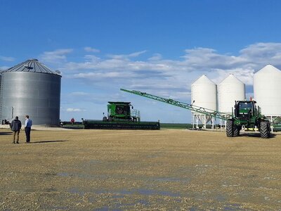 Verschiedene Landwirtschaftsmaschinen vor mehreren Getreidespeichern