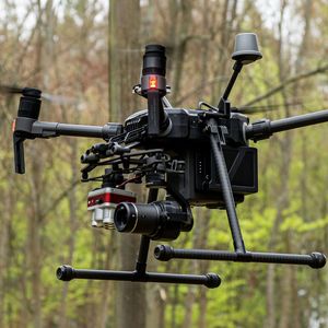 Nahaufnahme einer Drohne im Flug vor einem Baumbestand