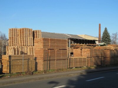 Stapel mit Schnittholz und Paletten liegen auf einem Hof im Freien