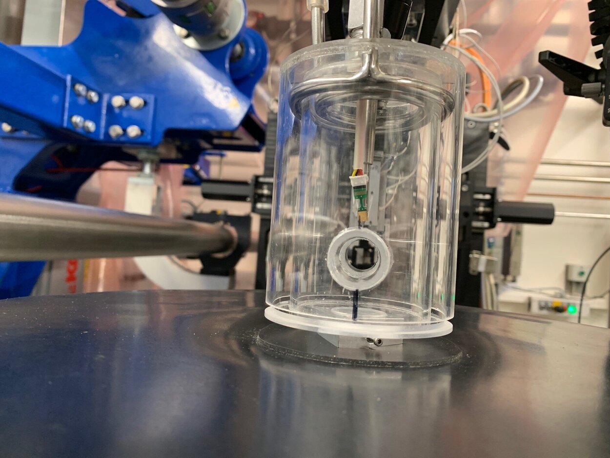 Ein gläserner Zylinder mit einem kleiinen elektronischem Gerät innen. 