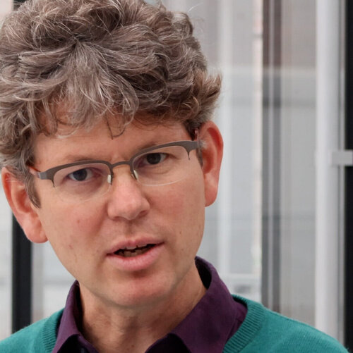 Mann mit grauen Locken und Brille erklärt etwas. Sein Gesichtsausdruck ist konzentriert.