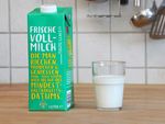 Ein Glas mit Milch gefüllt und daneben ein Tetrapack Milch mit einer Aufschrift die fordert nach dem Ablauf des Mindeshaltbarkeitsdatums noch zu probieren