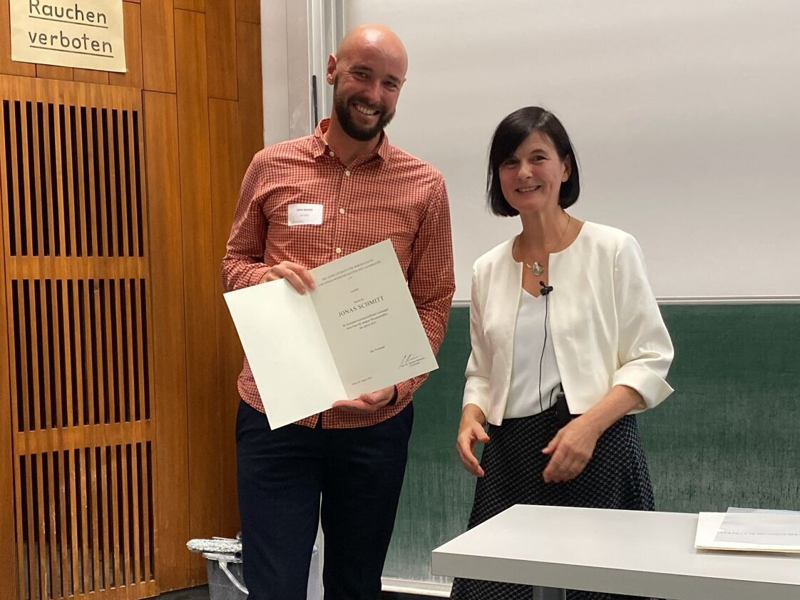 Two people, one of whom is holding a document in their hands.