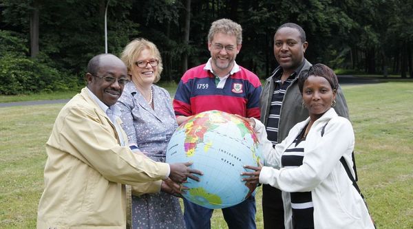 Fünf verschiedene Personen halten zusammen eine aufblasbare Weltkugel, die Afrika zeigt