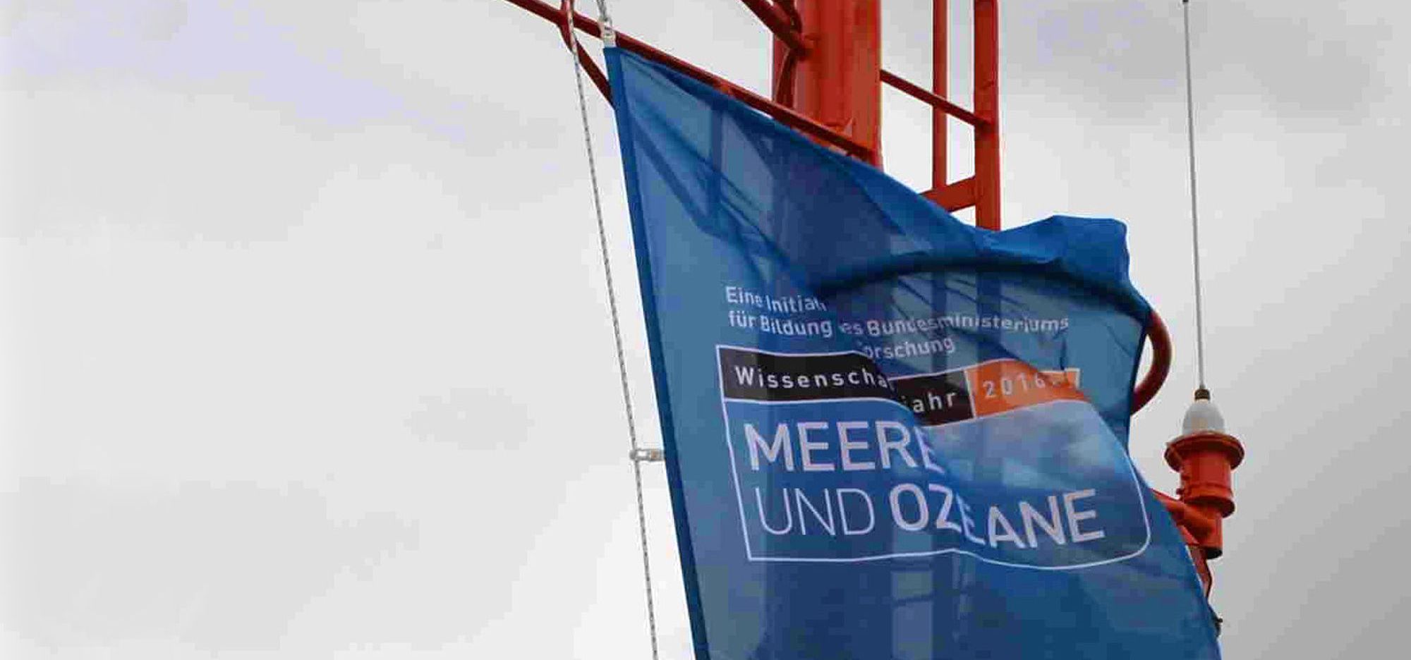 Eine Flagge mit der Aufschrift "Wissenschaftsjahr 2016: Meere und Ozeane" am Mat des Forschungsschiffs.
