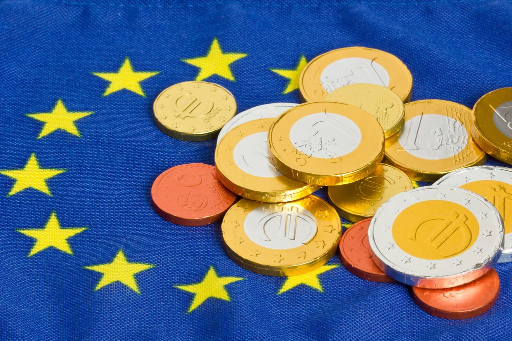 Europa und Euro, falsche Euromünzen liegen auf der Europafahne