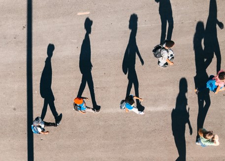 People shot from above walking along a path so that their shadows are clearly visible on the ground.