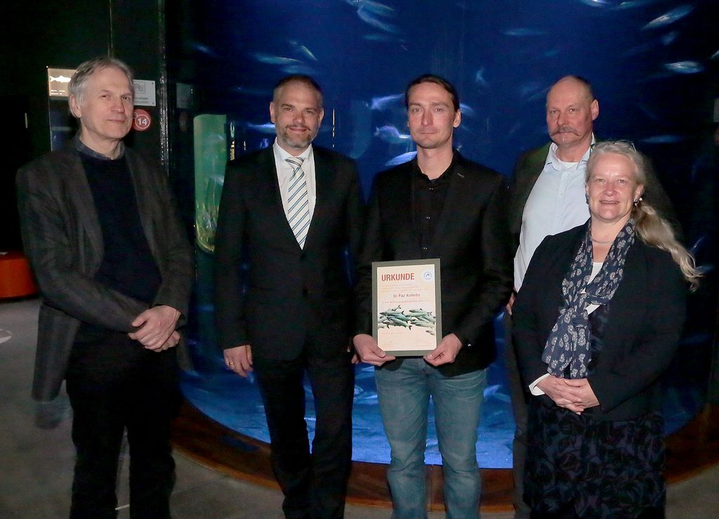 Dr. Henning von Nordheim (Stiftungsrat FSO), Dr. Alexander Badrow (Stiftungsratsvorsitzender FSO), Dr. Paul Kotterba (Preisträger), Andreas Tanschus (Vorstandsvorsitzender FSO), Dr. Sabine Brasse (Stellv. Stiftungsratsvorsitzende FSO) vor dem Heringsaquarium des OZEANEUMs.