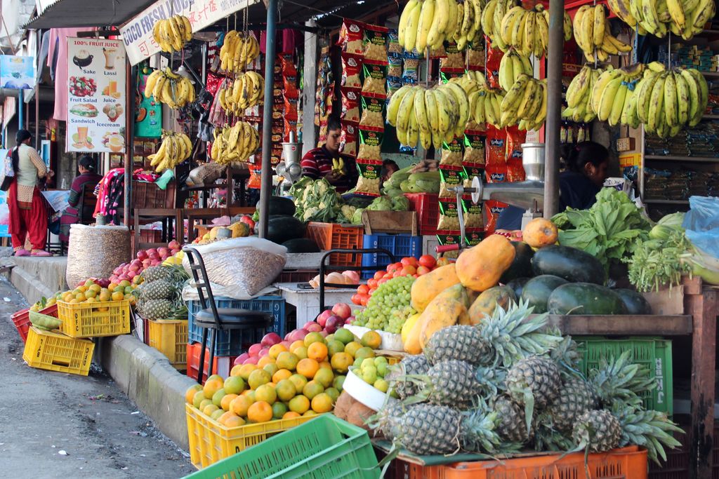 Ein Einkaufsstand in Nepal, im Vordergrund viel Obst und Gemüse, allerdings auch Erfrischungen und Chips
